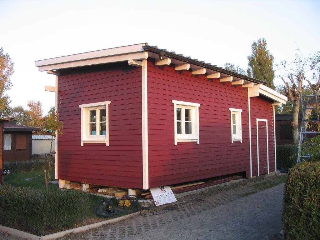 Rotes Gartenhaus mit weißen Fensterrahmen in skandinavischer Optik