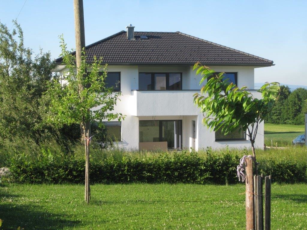 Haus mit dunklem Dach und langen Fenstern im ländlichen Raum